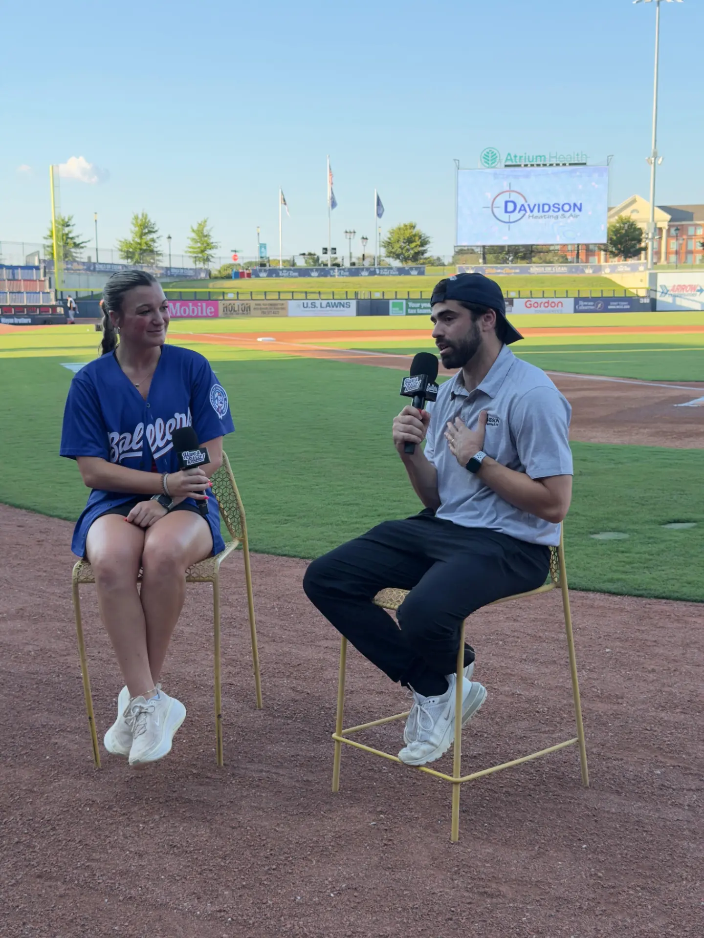 Davidson Heating & Air interview on the field at Atrium Health Ballpark during Bark in the Park in Kannapolis, with the company name on the videoboard