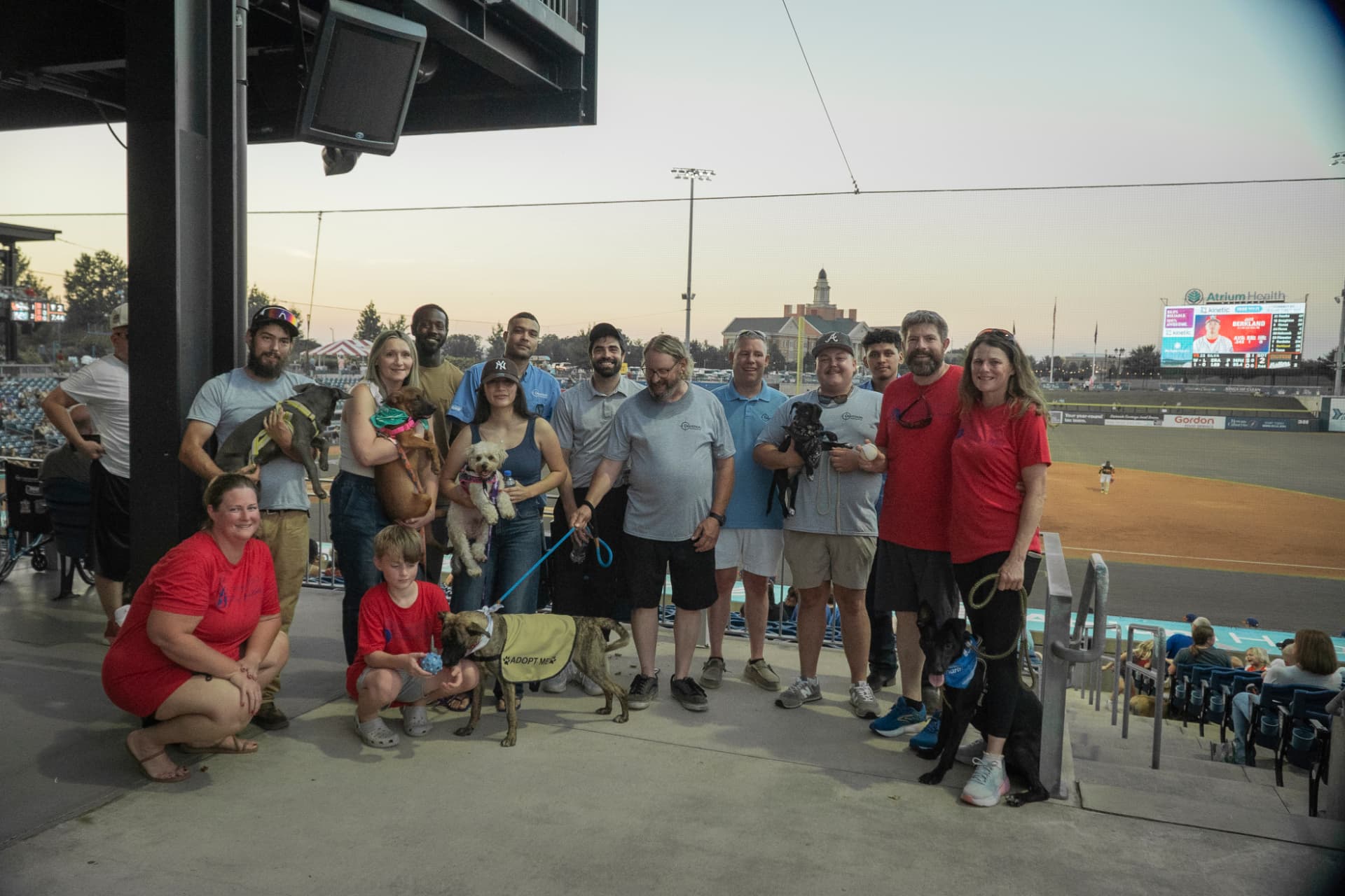Project Pawz volunteers and Davidson Heating & Air staff holding rescue dogs at Atrium Health Ballpark